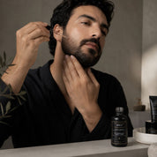 Application de L'Huile Confort Hendiya sur le visage et la barbe d'un homme, quelques gouttes déposées dans la paume pour un massage nourrissant au quotidien.