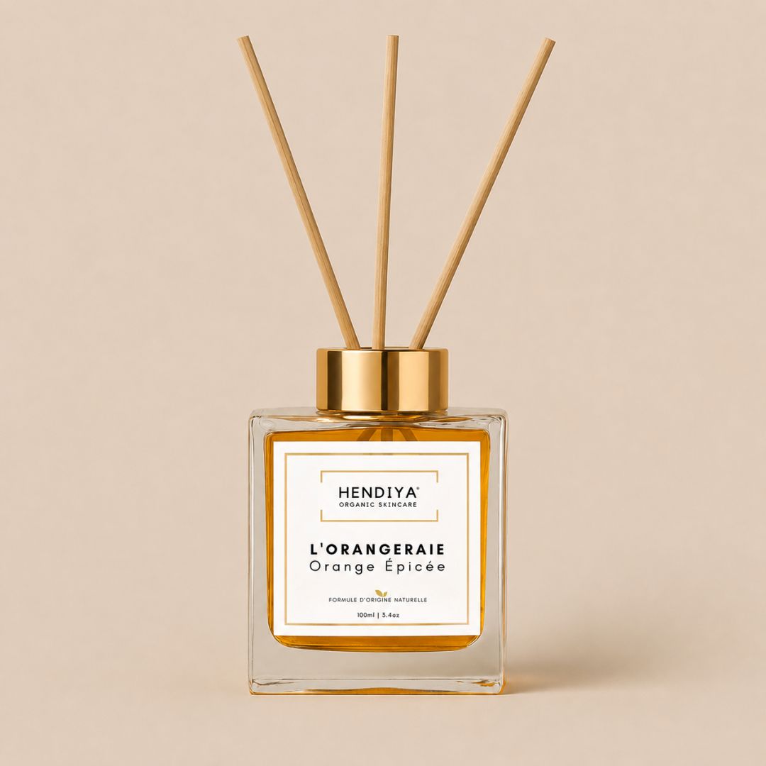 Flacon diffuseur Parfum d'Ambiance l'Orangeraie Hendiya, senteur orange épicée et écorces de cannelier, format 100ml avec ses tiges de rotin, présenté seul sur fond beige.